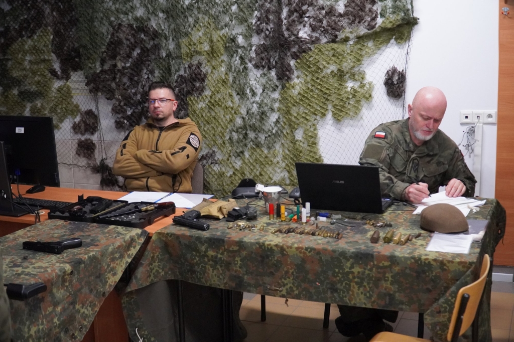 Uczestnicy I Wojewódzkich Zawodów Klas Mundurowych przy stolikach z wyposażeniem.