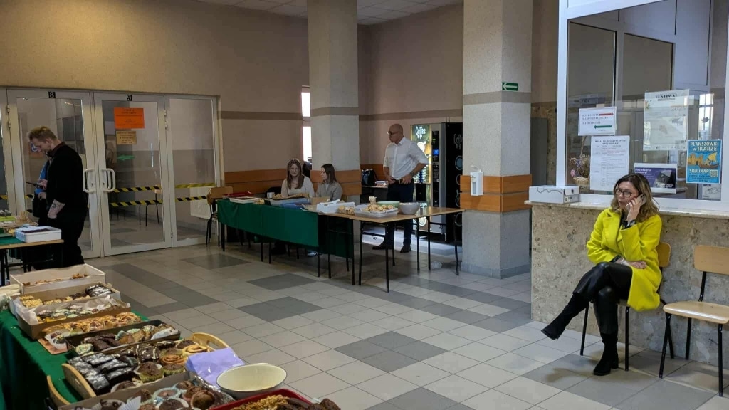 Kiermasz ciast na Wydziale Humanistycznym PANS w Jarosławiu: stoły z wypiekami, ludzie.