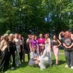 Grupa młodych kobiet w wiankach na głowach podczas pikniku rodzinnego w parku.