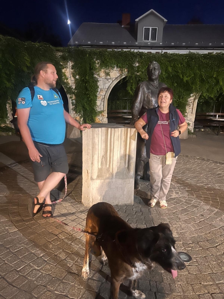 Ludzie i pies przy pomniku podczas warsztatów storytellingu.