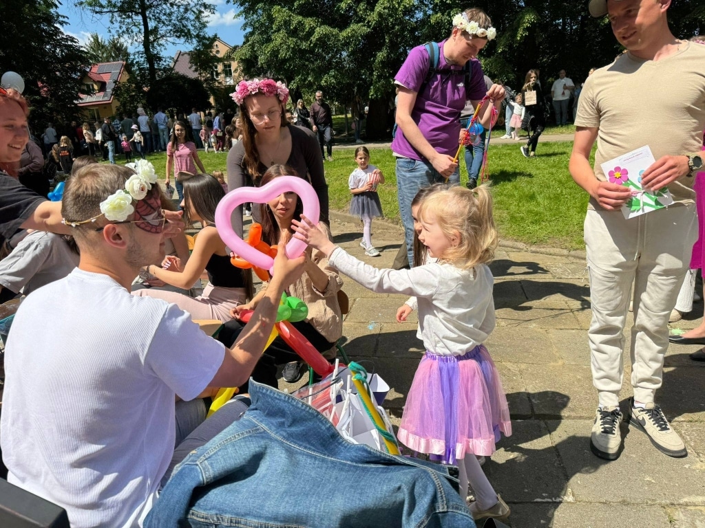 Dzieci na pikniku rodzinnym bawią się balonami w kształcie serca.