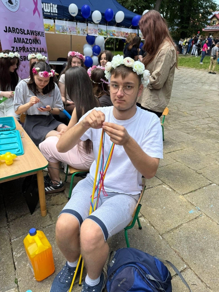 Chłopak z wiankiem na głowie robi bransoletkę na pikniku rodzinnym