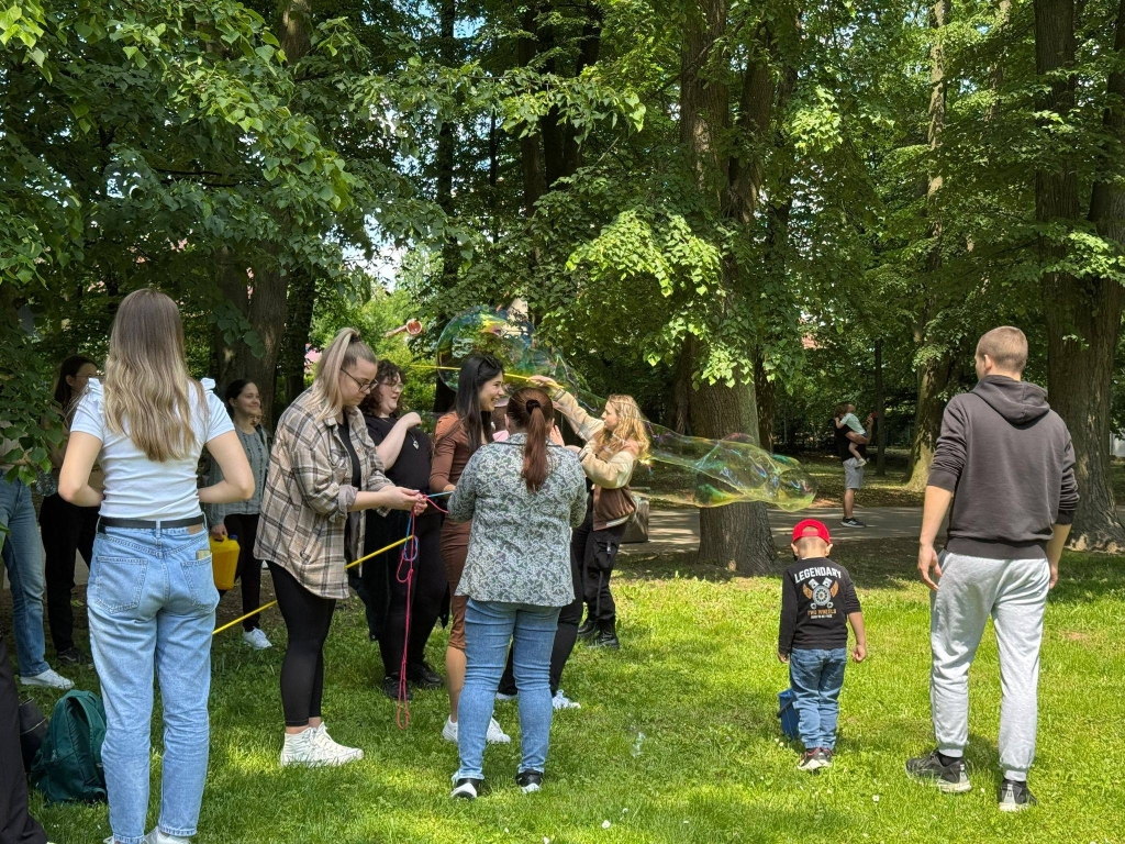 Dzieci i dorośli puszczają bańki mydlane na pikniku rodzinnym.