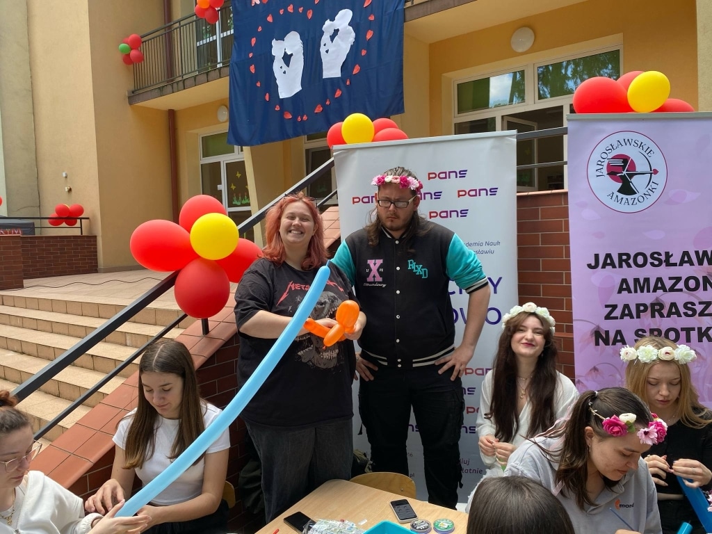 Piknik rodzinny: para z balonem i uczestnicy w wiankach