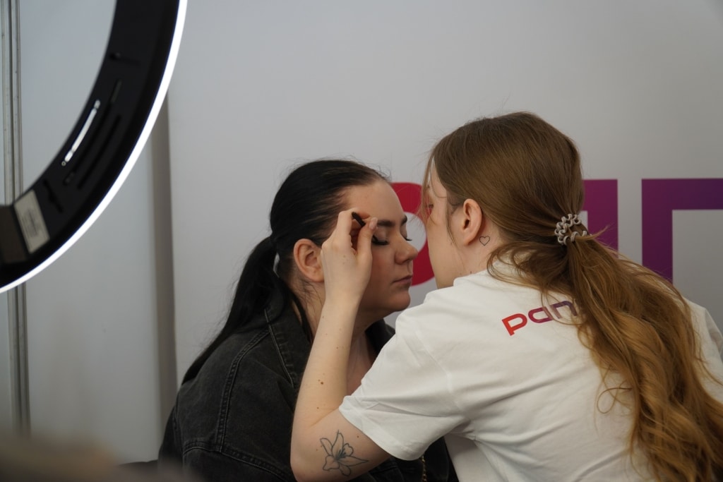 Makijażystka wykonuje makijaż na targach Edukacyjnych Edu Salon.