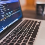 Laptop displaying code, keyboard, and coffee mug - ideal for online safety workshops.