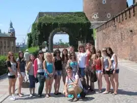 Grupa studentów na praktykach studenckich przed historyczną bramą