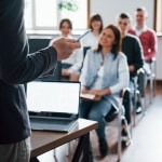 Nauczyciel prowadzi szkolenie dla grupy studentów, omawiając innowacyjne metody nauczania.