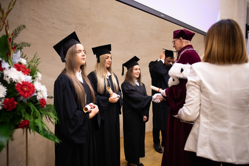Inauguracja 2021/2022: absolwenci odbierają dyplomy od profesora.
