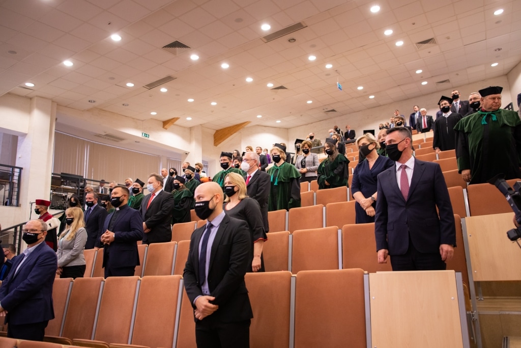 Inauguracja roku akademickiego 2021/2022: uczestnicy w togach i maskach siedzą w sali.