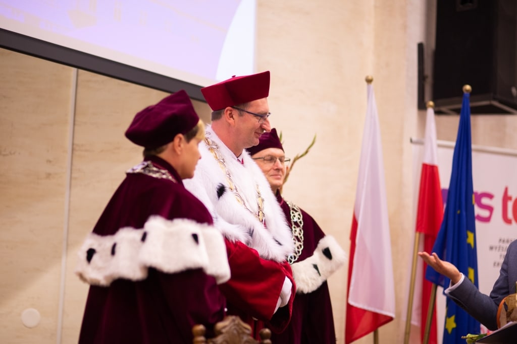 Inauguracja 2021/2022: Profesorowie w togach na tle flag