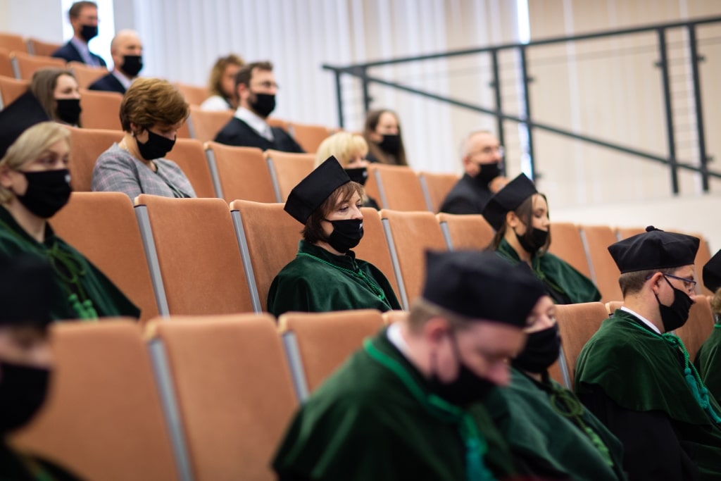 Uczestnicy inauguracji 2021/2022 w togach i biretach na sali wykładowej.