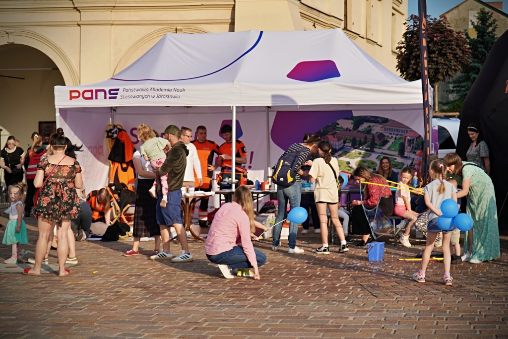 Ludzie podczas Juwenaliów 2025 pod namiotem PANS z napisem "Państwowa Akademia Nauk Stosowanych w Jarosławiu".