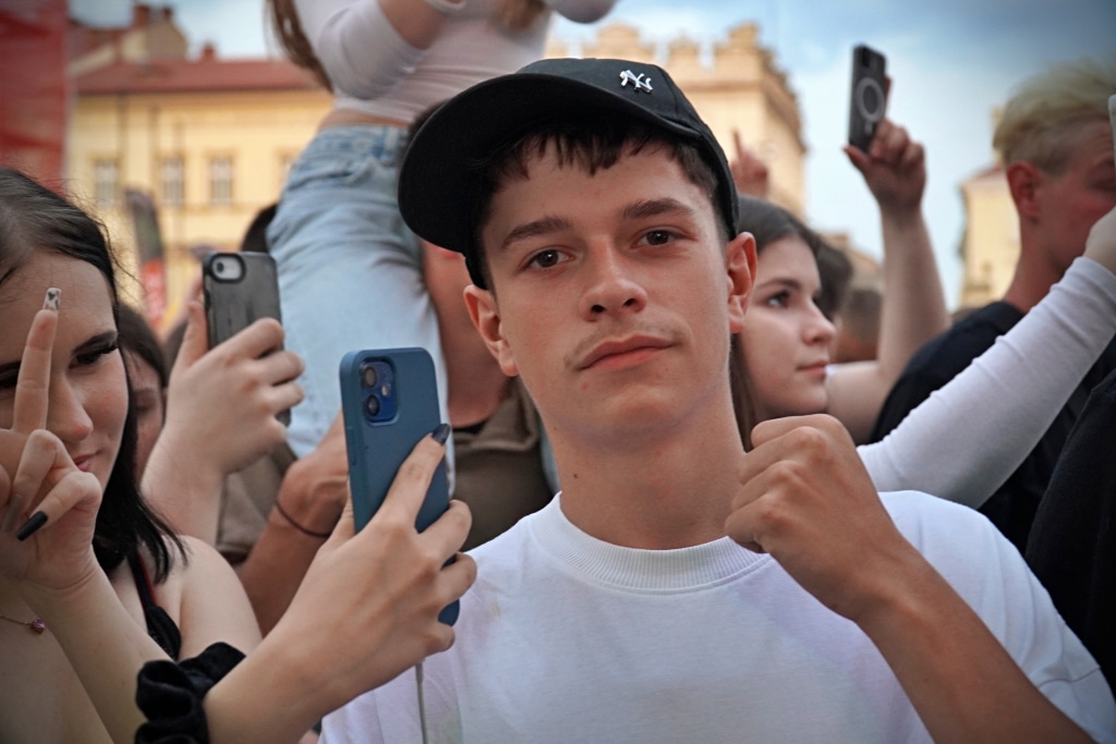 Młodzi ludzie na Juwenaliach 2025, jeden z nich robi zdjęcie telefonem