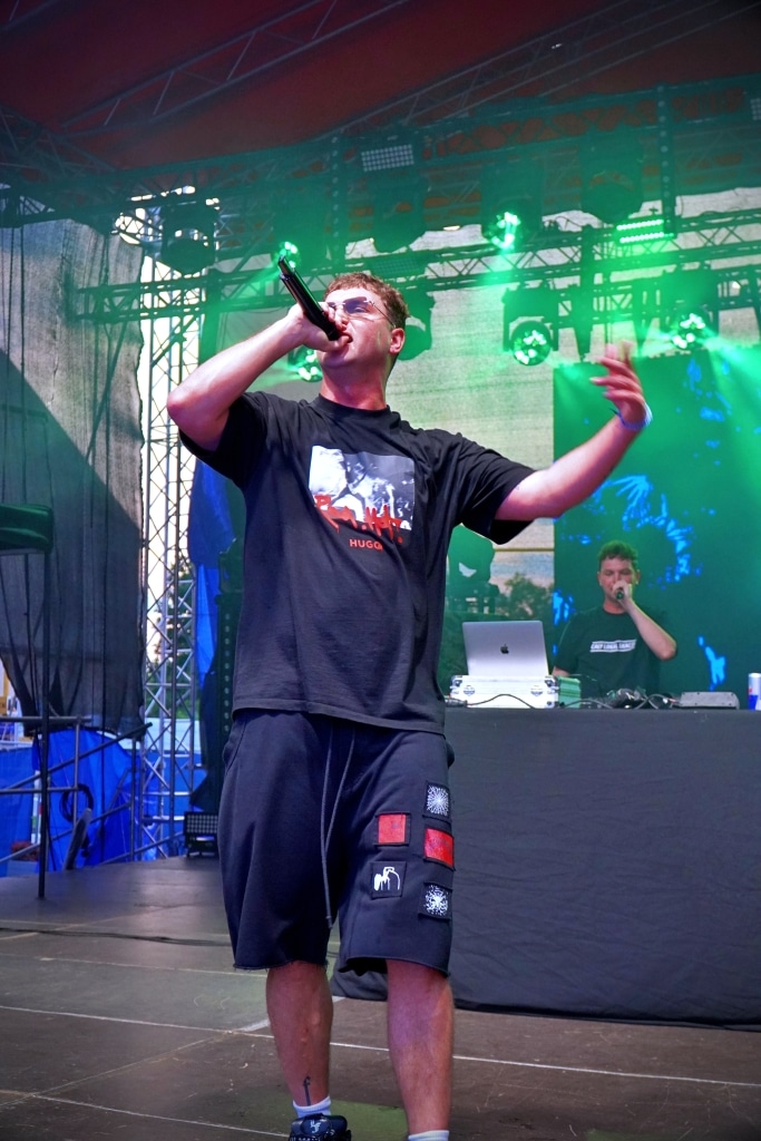 Raper na scenie Juwenaliów 2025 z mikrofonem, DJ w tle