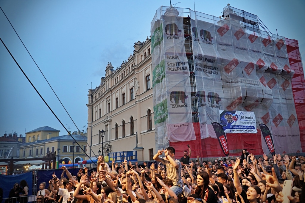 Tłum ludzi na Juwenaliach 2025 przed budynkiem z rusztowaniem i banerami Caparol.
