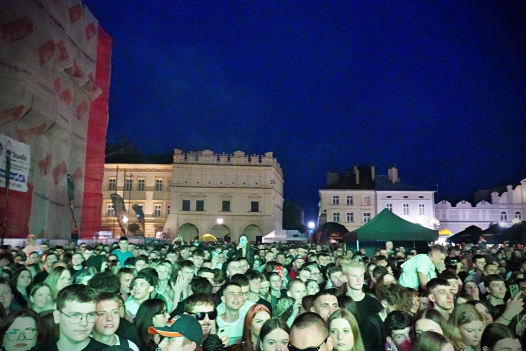Tłum ludzi podczas Juwenaliów 2025, nocne wydarzenie plenerowe z budynkami w tle.