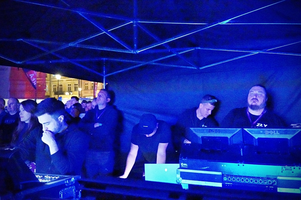 Ludzie na Juwenaliach 2025 pod niebieskim namiotem z DJ-ami przy sprzęcie.