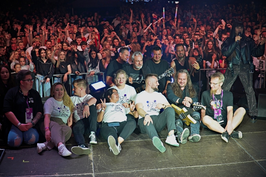 Grupa młodych ludzi na scenie podczas Juwenaliów 2025 z publicznością w tle.