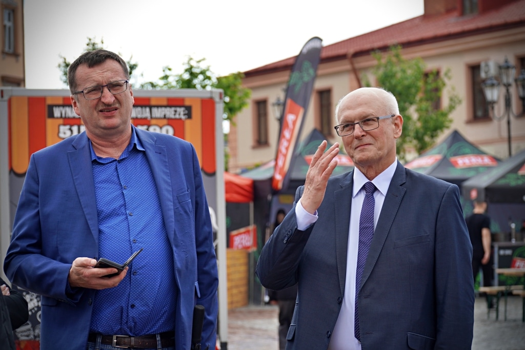 Mężczyźni w garniturach na tle stoisk Juwenalia 2025