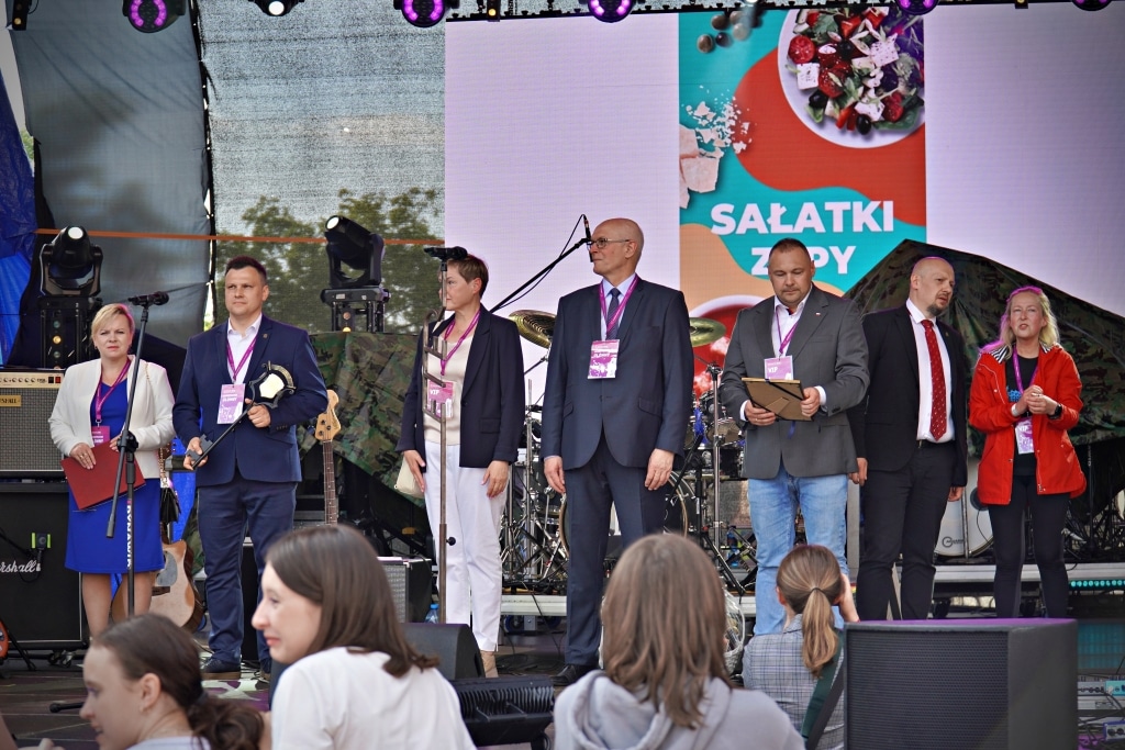 Grupa osób na scenie podczas Juwenaliów 2025, z banerem "Sałatki Zupy