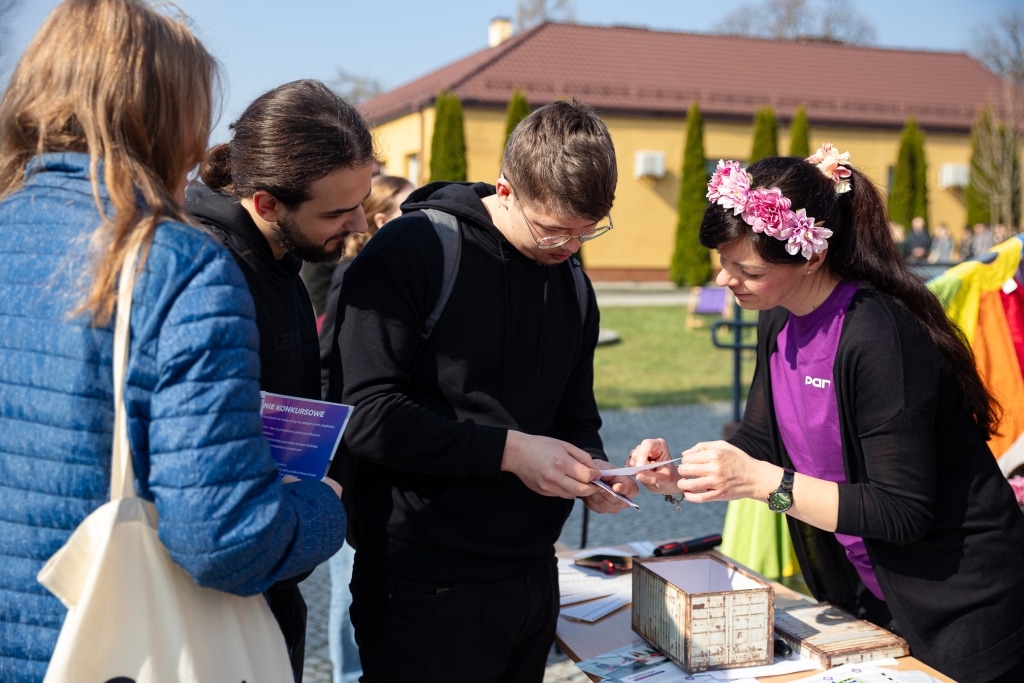 Uczestnicy Dnia Otwartego 2025 rozmawiają przy stoliku z materiałami informacyjnymi.
