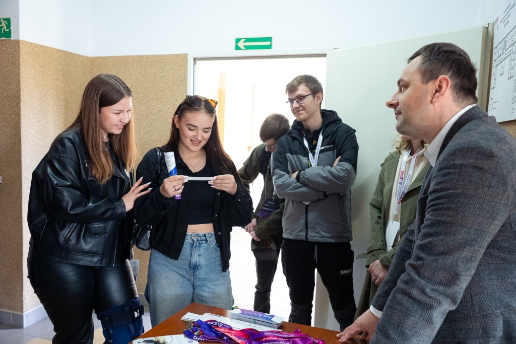 Grupa młodych ludzi na Dniu Otwartym 2025, rozmawiająca przy stole