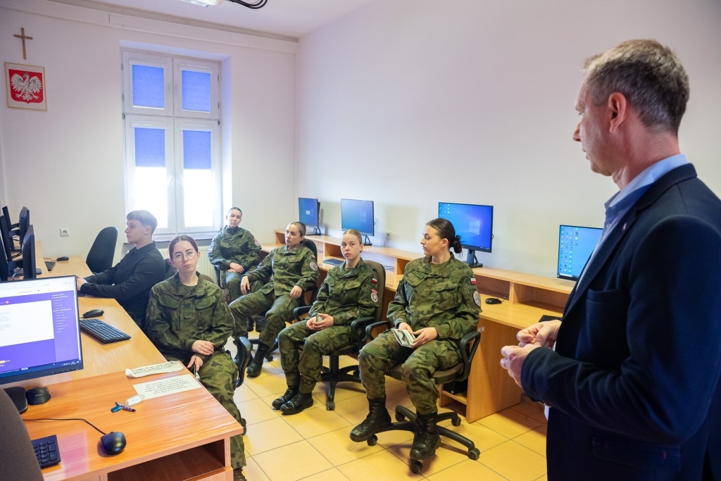 Dzień Otwarty 2025: Mężczyzna przemawia do studentek w mundurach wojskowych w sali komputerowej.
