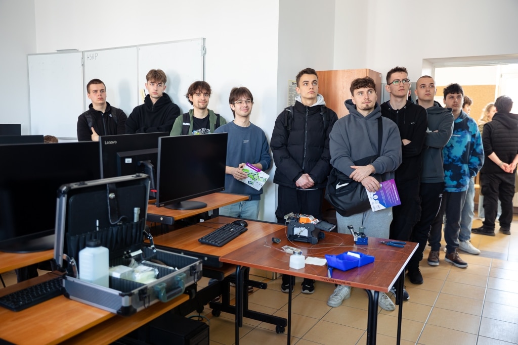 Grupa studentów na Dniu Otwartym 2025 w sali lekcyjnej z komputerami.