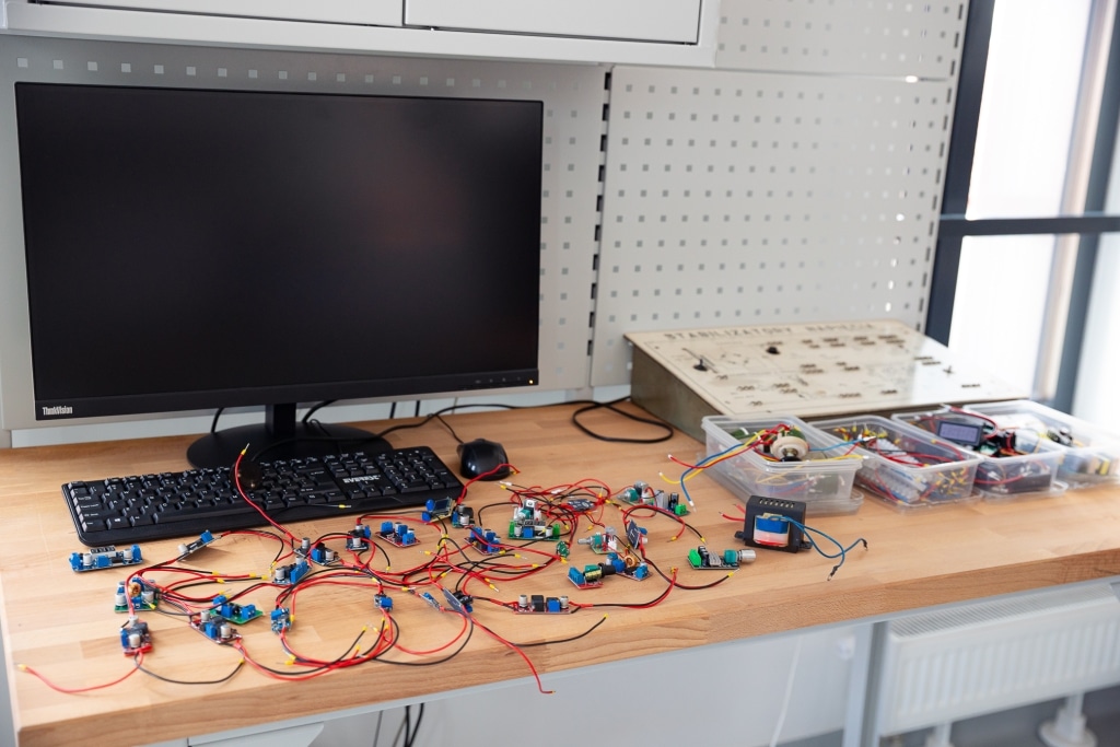 Stół z komputerem, klawiaturą i przewodami elektronicznymi do eksperymentów.