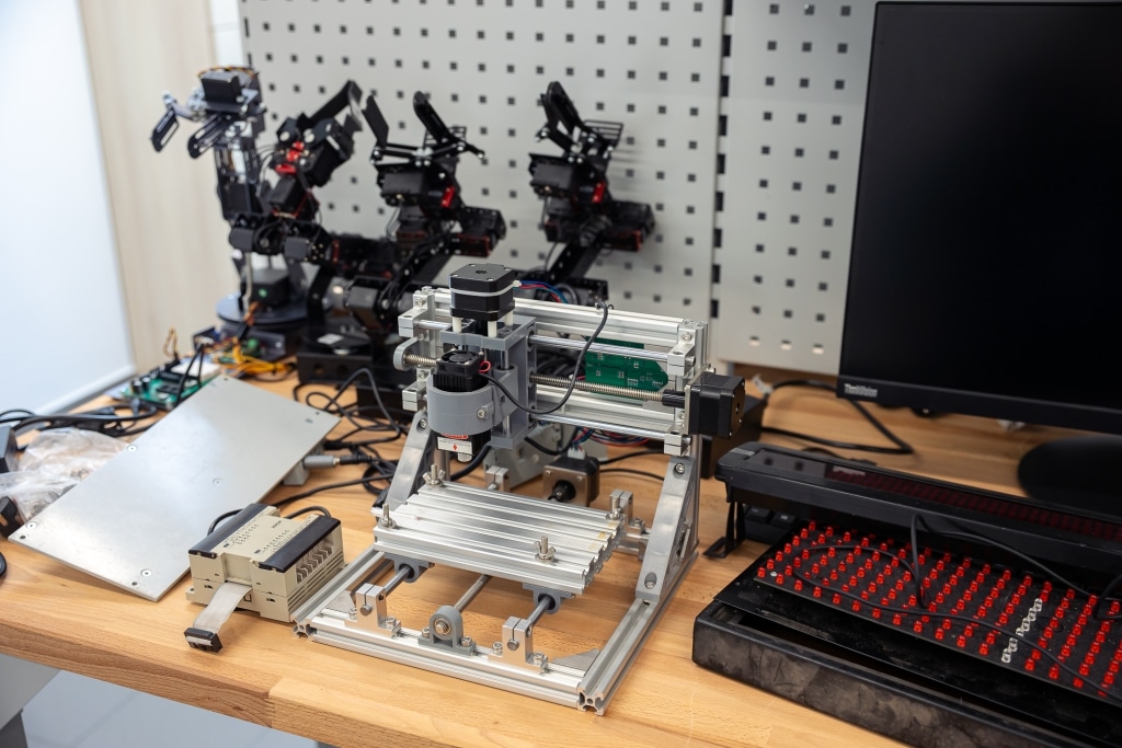Stół z drukarką 3D, robotami i komputerem na Dzień Otwarty 2025.