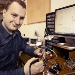 Student elektroniki pracuje przy biurku z komputerem i narzędziami