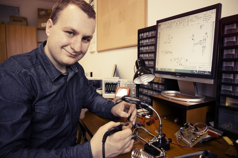Student elektroniki pracuje przy biurku z komputerem i narzędziami