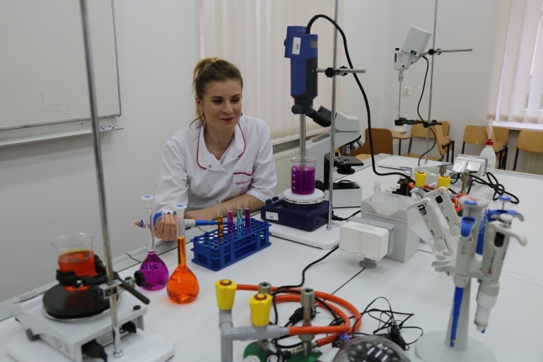 Studentka w laboratorium bada płyny w probówkach, baza dydaktyczna