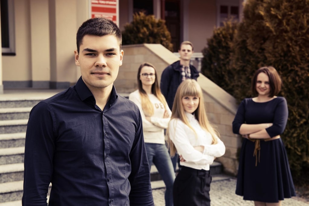 Grupa studentów przed budynkiem uczelni