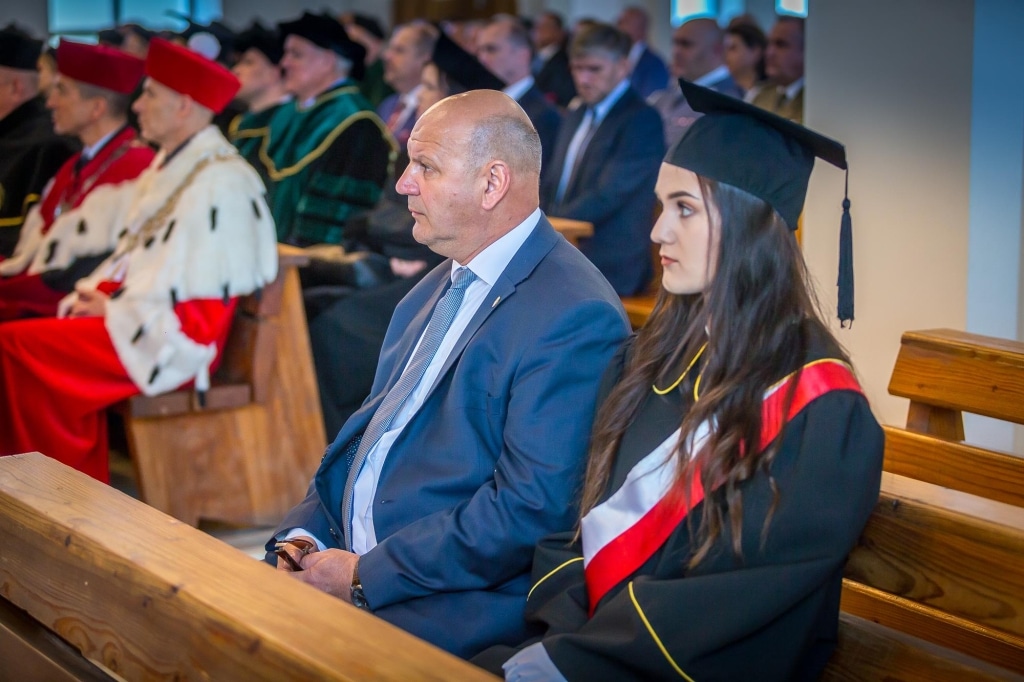 Inauguracja 2018/2019: Uczestnicy w togach siedzą na drewnianych ławkach