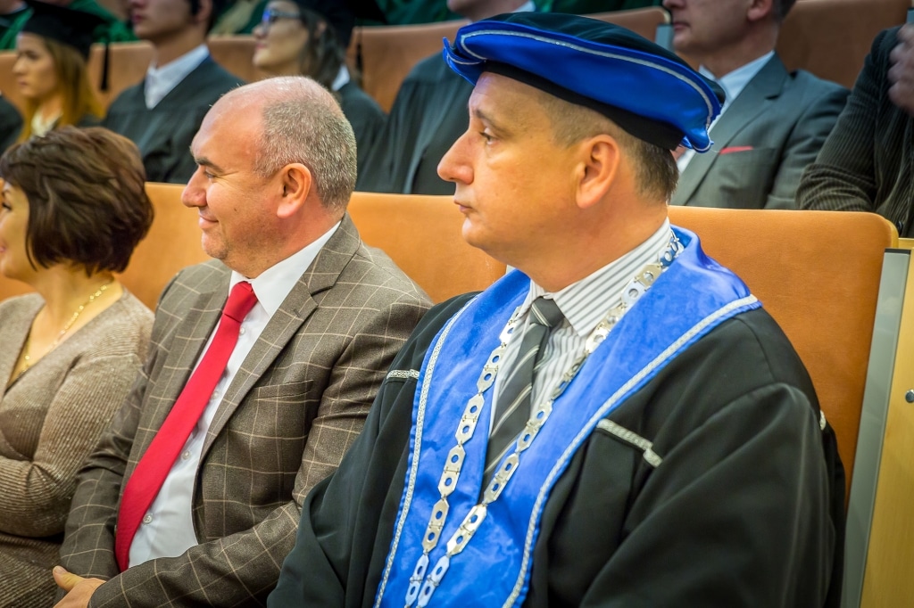 Inauguracja 2018/2019: Profesorowie w togach i biretach siedzą na uroczystości.
