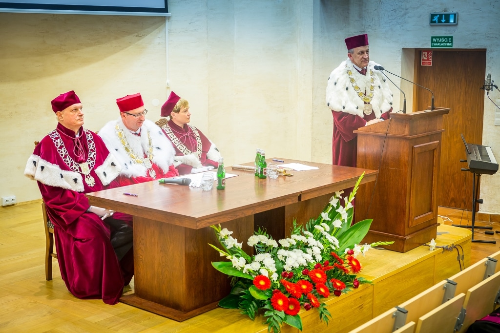 Inauguracja 2018/2019: Rektor przemawia, profesorowie w togach przy stole.