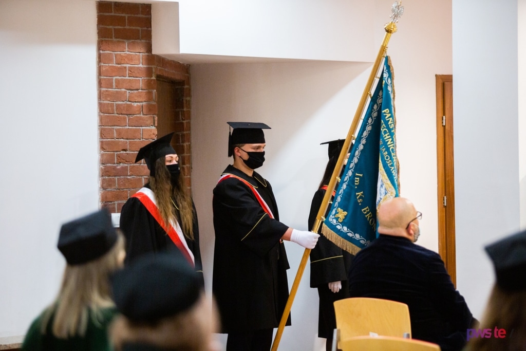 Inauguracja 2020/2021: studenci w togach i biretach z flagą uczelni