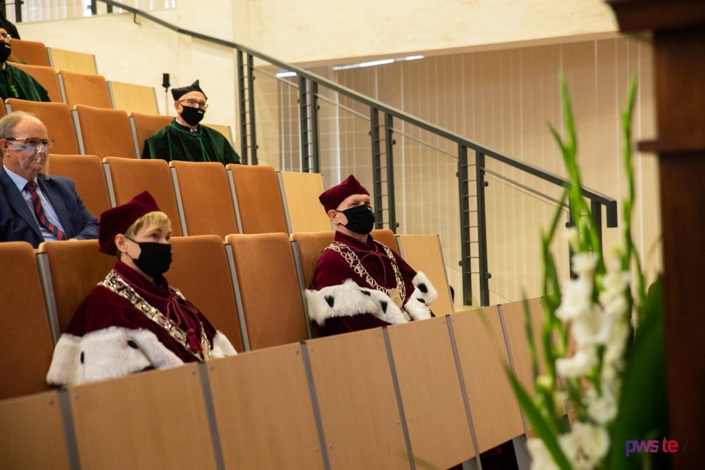 Inauguracja roku akademickiego 2020/2021: profesorowie w togach siedzą w auli.